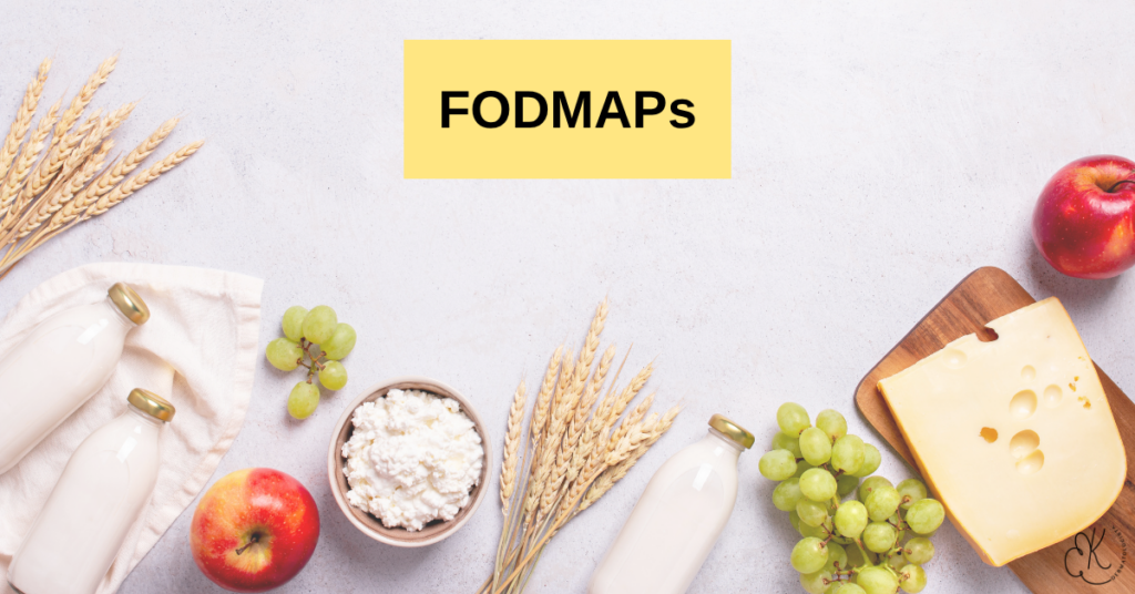 Leite, queijo, uvas, maçãs e trigo dispostos em uma superfície clara com a palavra FODMAPs
