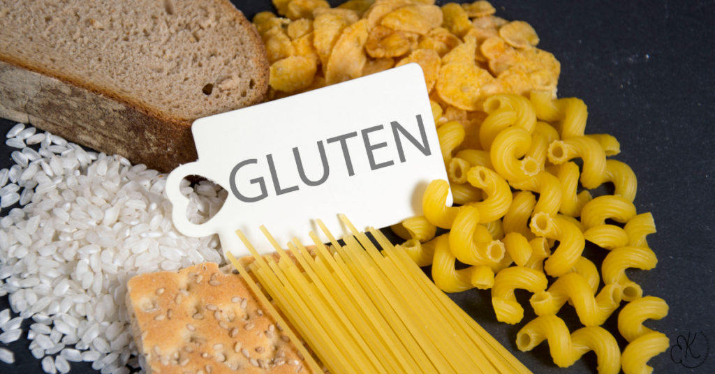 Tag com a palavra “GLUTEN” sobre pães, biscoitos, massas e grãos.